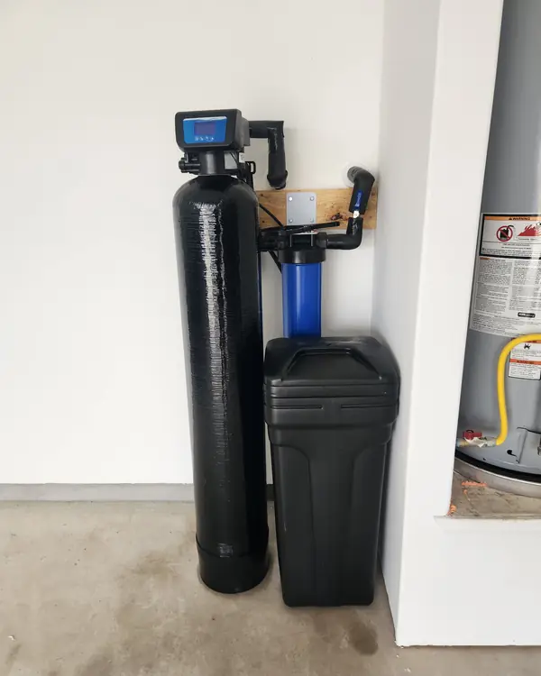 Water softener with whole-home filter in a garage corner