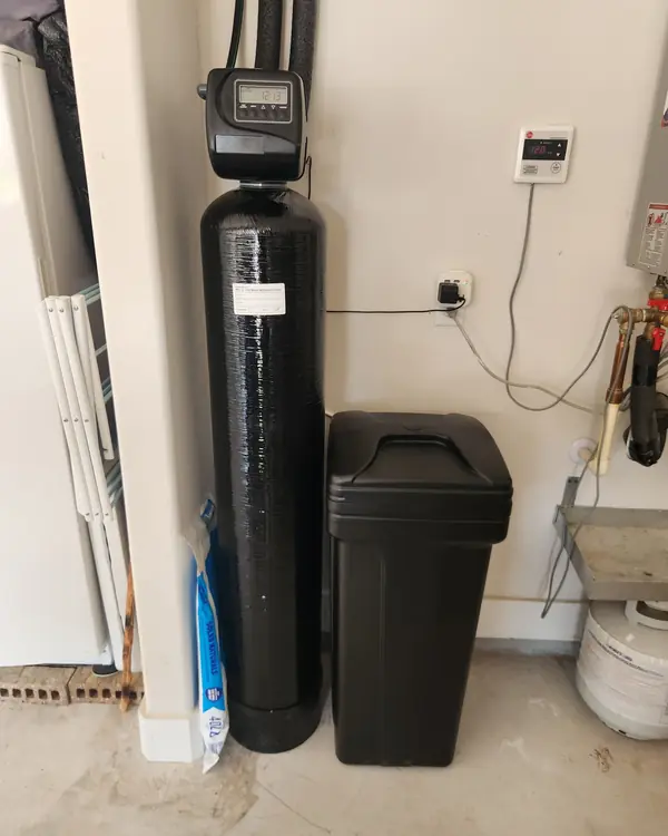 Water softener installed next to a gas water heater in a garage