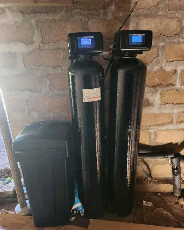 Two-tank water treatment system installed against a block wall